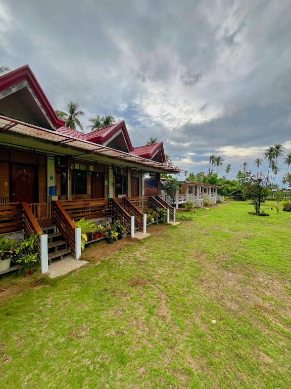a row of houses with a grass yard in front at Marianne's Guest House in New Agutaya