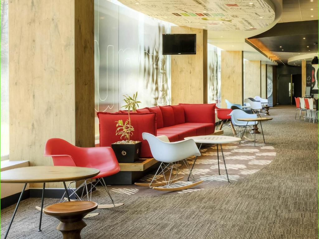 a lobby with a red couch and tables and chairs at Ibis Mexico Perinorte in Mexico City