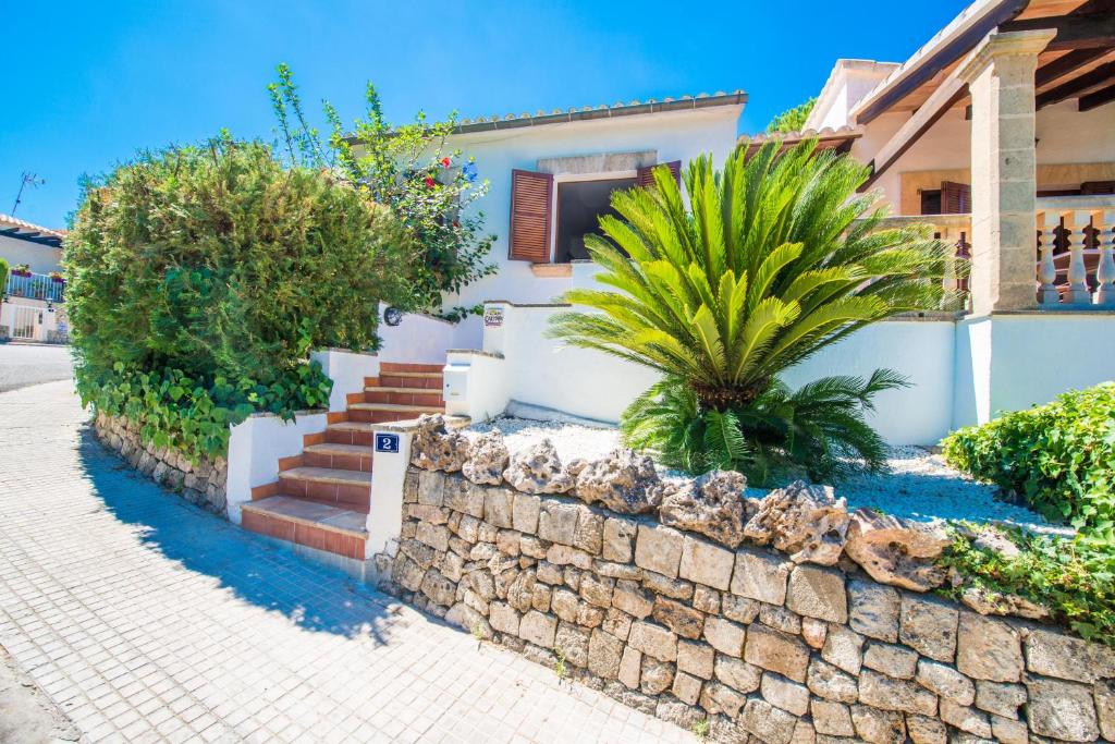 a house with a stone wall and palm trees at Can Caimari in Cielo de Bonaire 