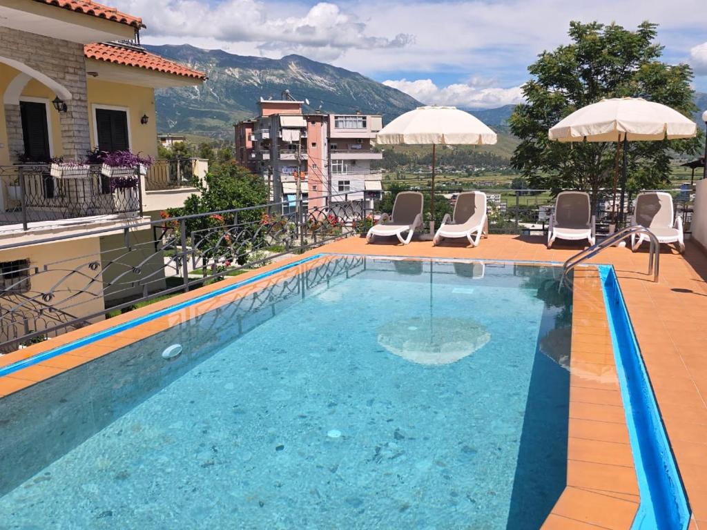 a swimming pool on top of a building with chairs and umbrellas at Villa Qeli in Gjirokastër