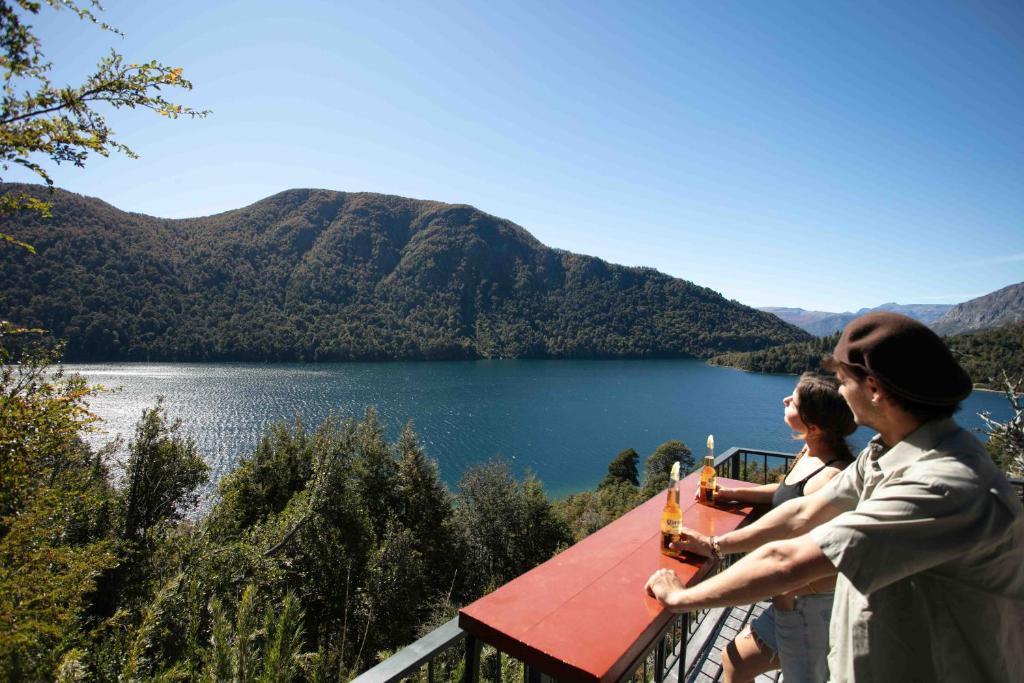 two people sitting at a table overlooking a lake at Hermoso Eco Lodge in San Martín de los Andes