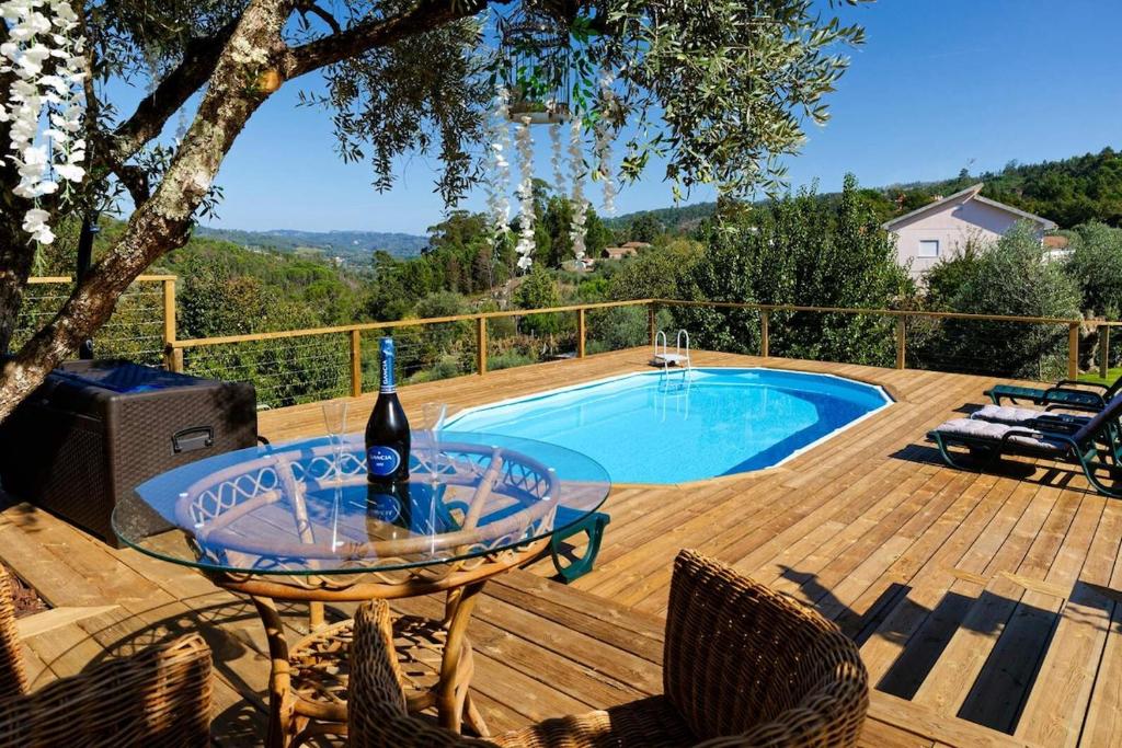 a table with a bottle of wine on a deck next to a pool at Refúgios do Rio Dão in Mangualde