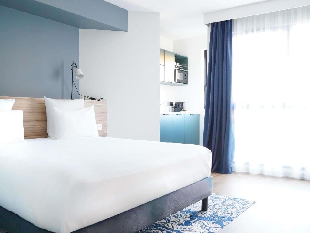 a bedroom with a large white bed and a window at AppartHotel Mercure Paris Boulogne in Boulogne-Billancourt