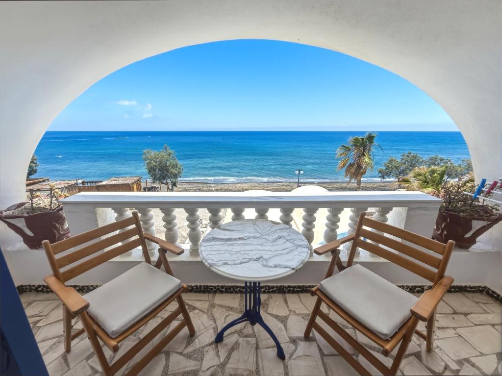 a balcony with a table and chairs and the ocean at Stavros Beachfront Domes by Booking Kottas in Perivolos
