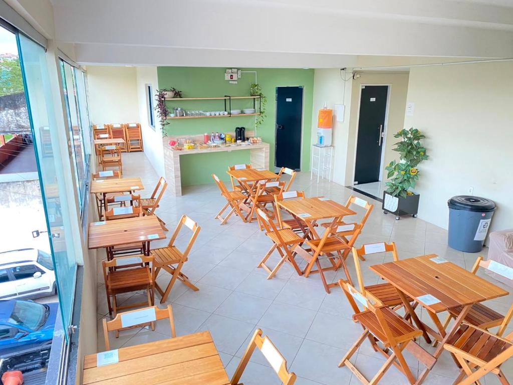 an empty restaurant with wooden tables and chairs at Hotel Renascer pojuca in Pojuca