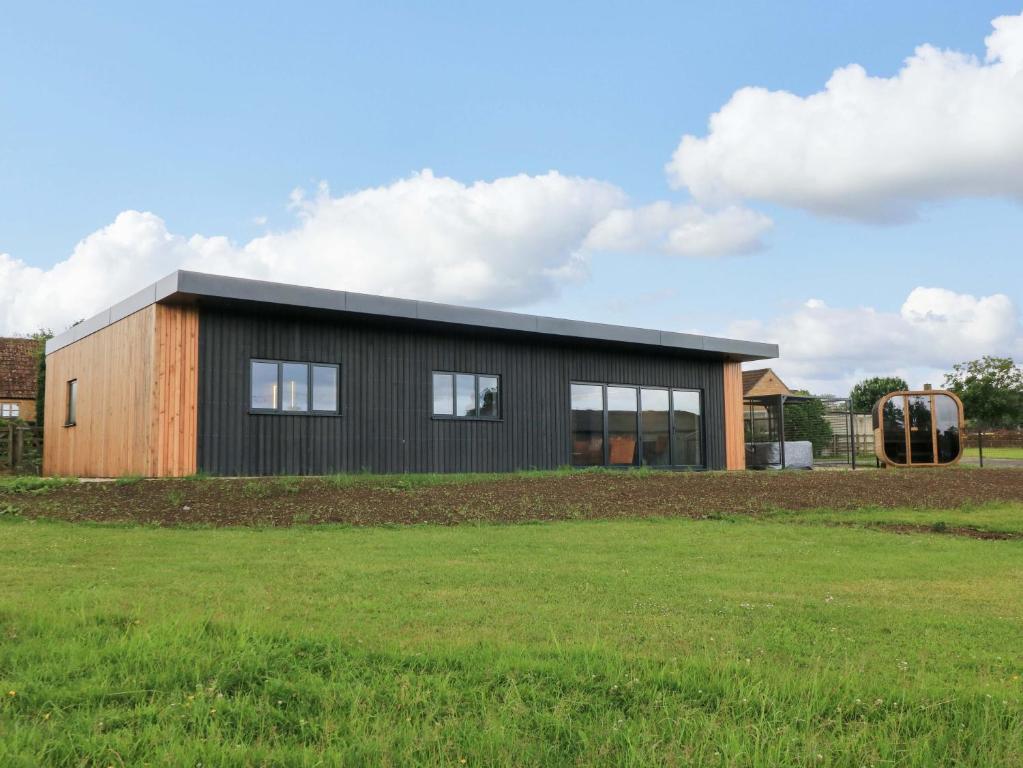 a brown and black building with a grass field at The Cozie Sow in Yeovil