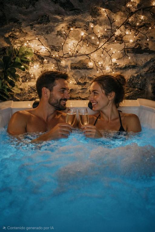 a man and woman in a hot tub with wine glasses at LARCADE Loft Industrial-Jacuzzi in Castillo de Bayuela