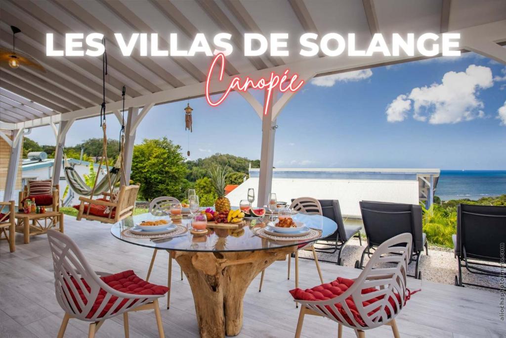 a table and chairs on a patio with a view of the ocean at La Villa de Solange - Canope in La Trinité