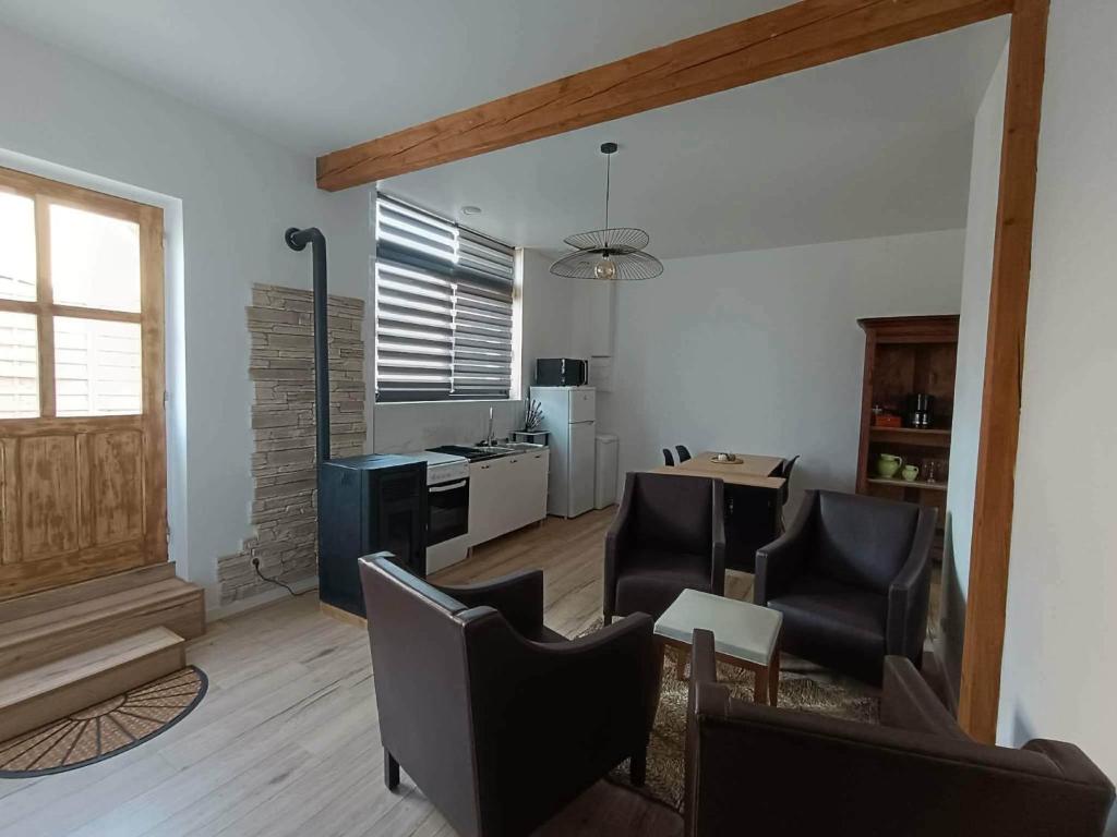 a living room with chairs and a table and a kitchen at Gîte aux 3 Cep in Magnien