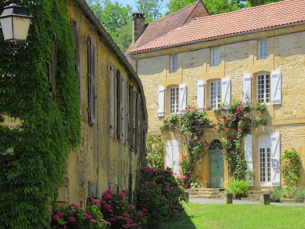 an old stone building with flowers and a green door at Maison Honorine in Saint-Geniès