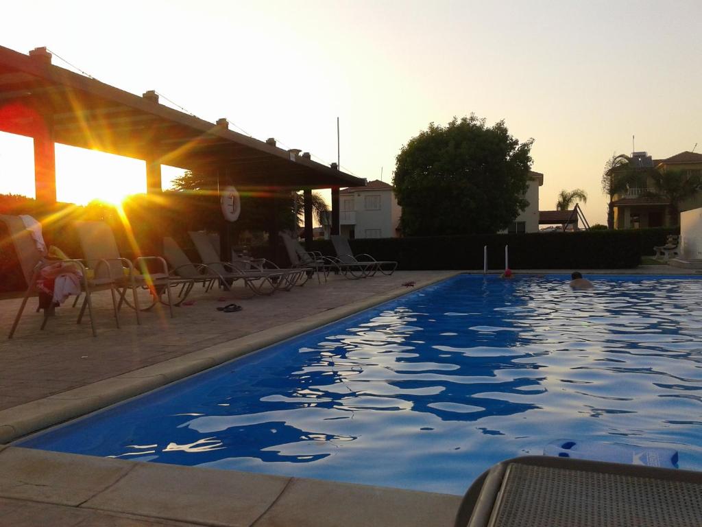 una piscina con el sol reflejándose en el agua en Sunset Garden Villa, en Perivolia