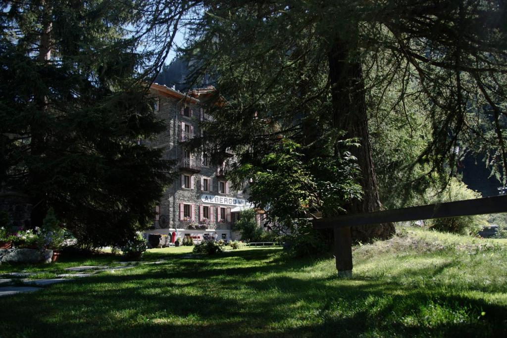 a building in the middle of a park with a bench at Albergo Monte Cervino in Champoluc
