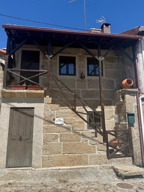a stone house with a wooden door and stairs at Casa do Campo in Montalegre