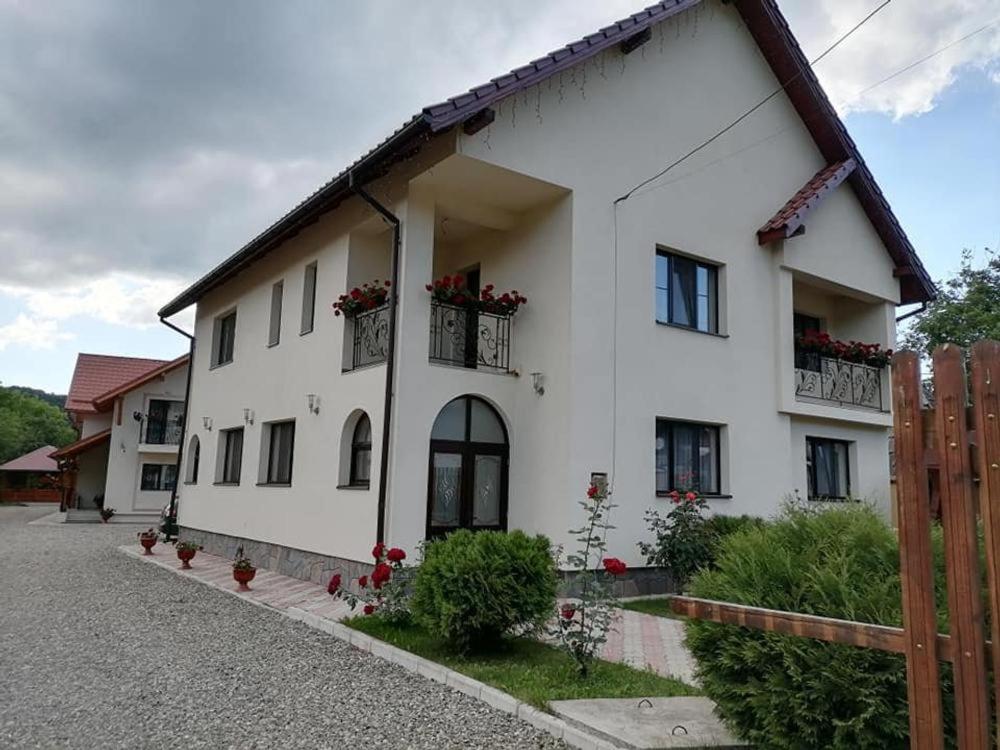 a white house with flower boxes on the windows at Pensiunea Baias in Bîrsana