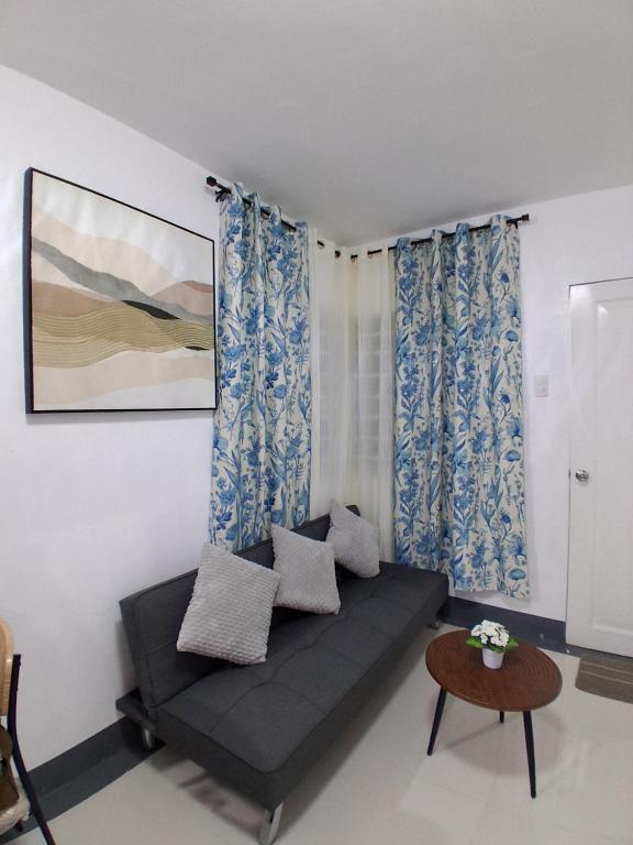 a living room with a black couch and blue curtains at Sorelle Bella Vita in Manolo Fortich