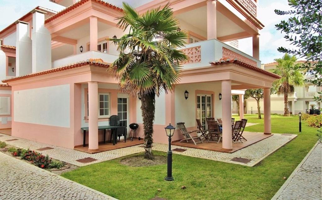 a pink house with a palm tree in the yard at Casa Lesarlo - T3 luxury, garden, pool - Praia D'El Rey in Casal da Lagoa Seca