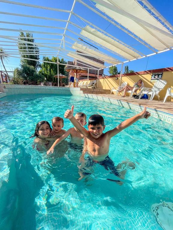 a group of children swimming in a swimming pool at Complejo Turistico Los Troncos in San Rafael