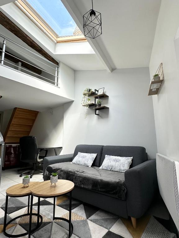a living room with a black couch and two tables at LE BORA - Duplex en Centre-ville - Puy-du-fouu in Cholet