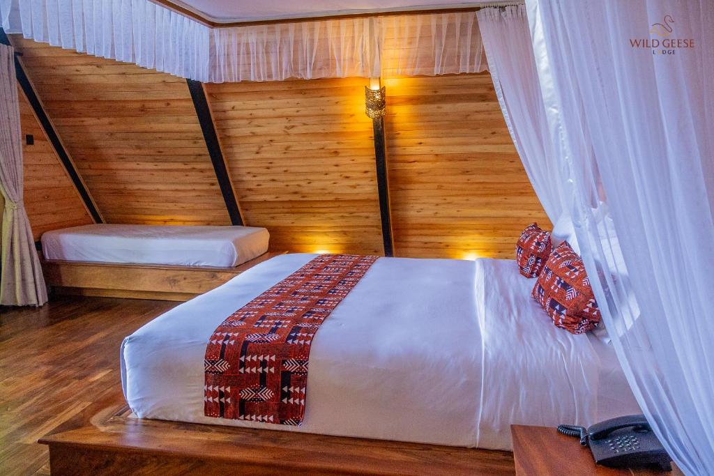 a bedroom with a bed in a room with wooden walls at Wild geese Lodge in Lulongo