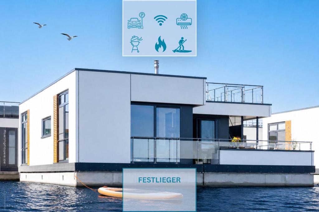 a house on the water with a sign in front at Floatinghouse Meerkraft in Ribnitz-Damgarten