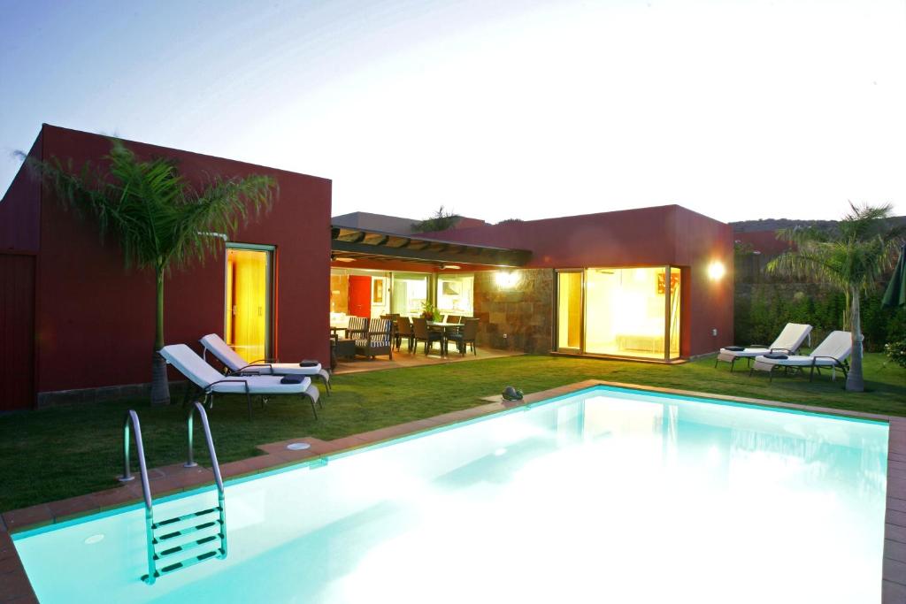 a swimming pool in front of a house at Villa Salobre Master and Sun in Maspalomas