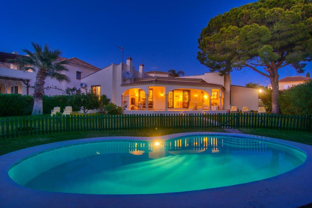 a swimming pool in front of a house at night at Beach House Las Chapas in Marbella