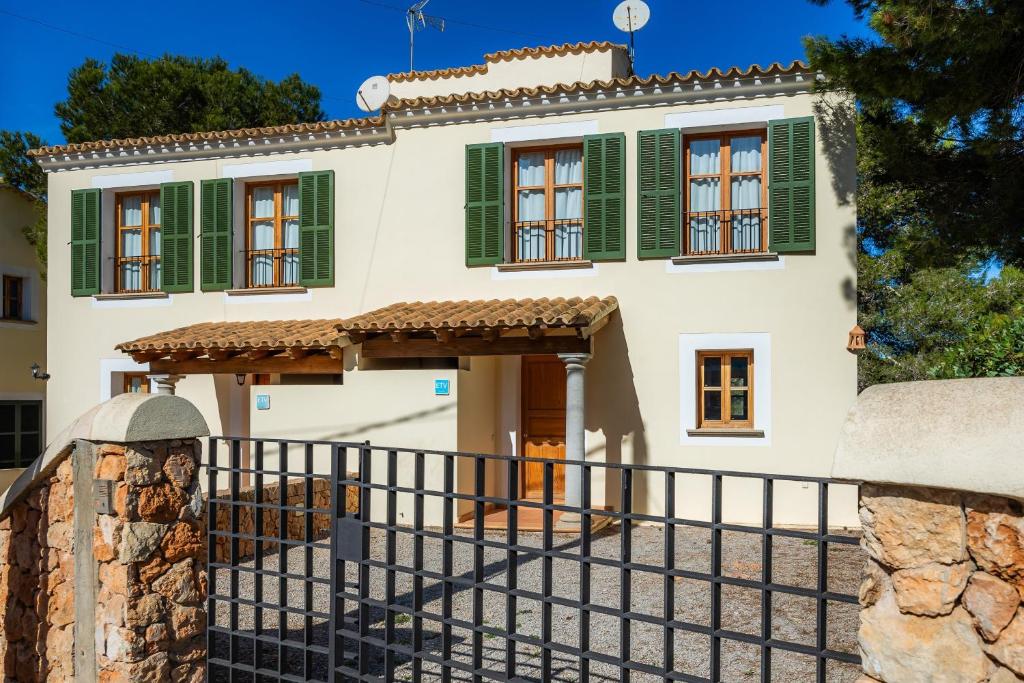 a house with green shutters and a fence at Cala Pi One in Cala Pi