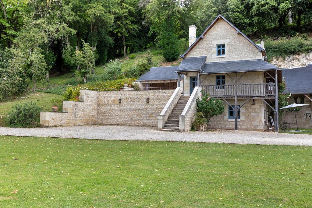 a large house with a stone wall and a staircase at Le Trianon Isabelle de Maillé - in Cravant-les-Coteaux