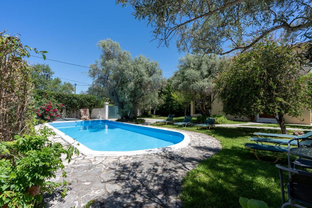 a swimming pool in a yard with chairs and trees at VK Villas in Apolpaina