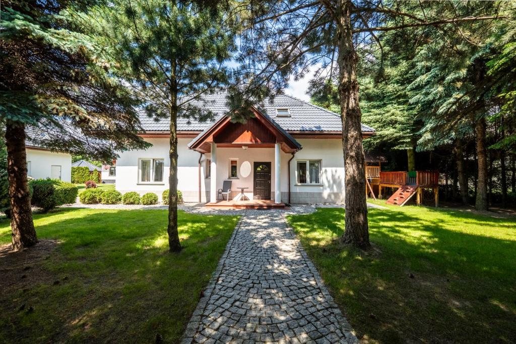 a white house with trees in the yard at Willa u Basi in Miłków
