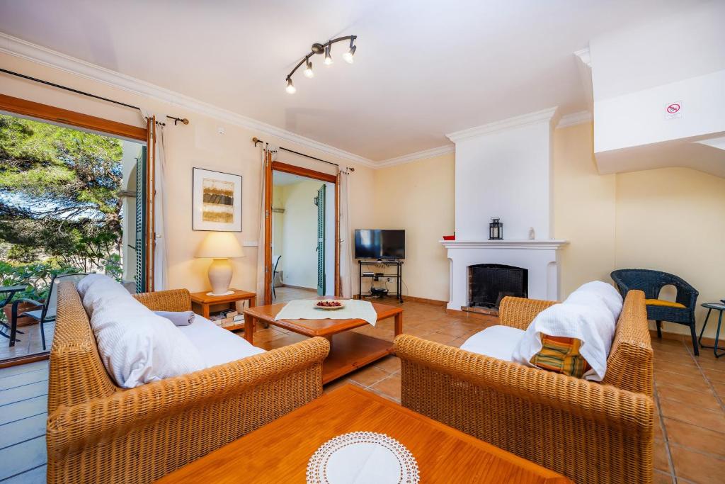a living room with wicker chairs and a fireplace at Cala Pi Two in Cala Pi