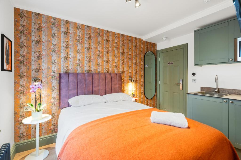 a bedroom with a large bed with an orange blanket at Upper Victoria in London