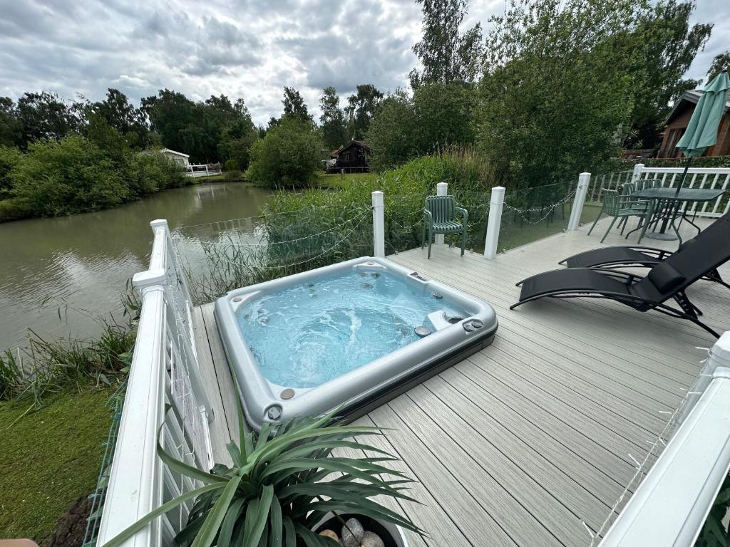 a hot tub sitting on a deck next to a river at Luxury Lakeside Lodge L2 with Hot tub situated at Tattershall Lakes Country Park in Tattershall