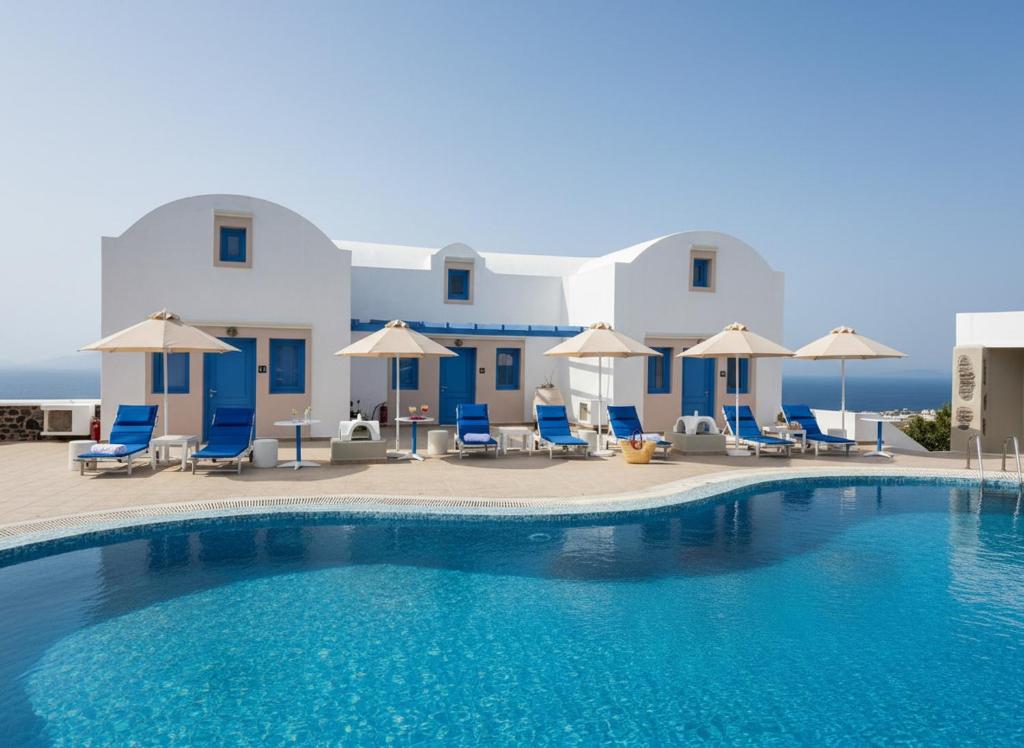 a pool with chairs and umbrellas in front of a building at White Pearl Laokasti Suites in Oia