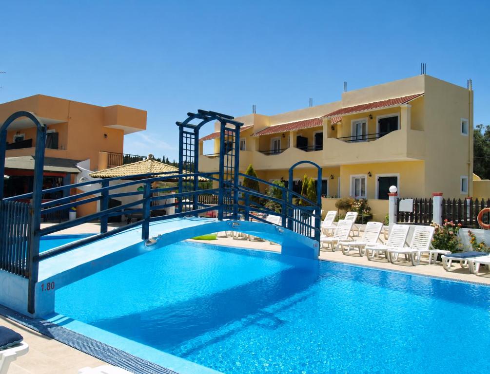 a pool with a slide in front of a house at Nikos Villas - Poolside Getaways in Kavos, Corfu in Kavos