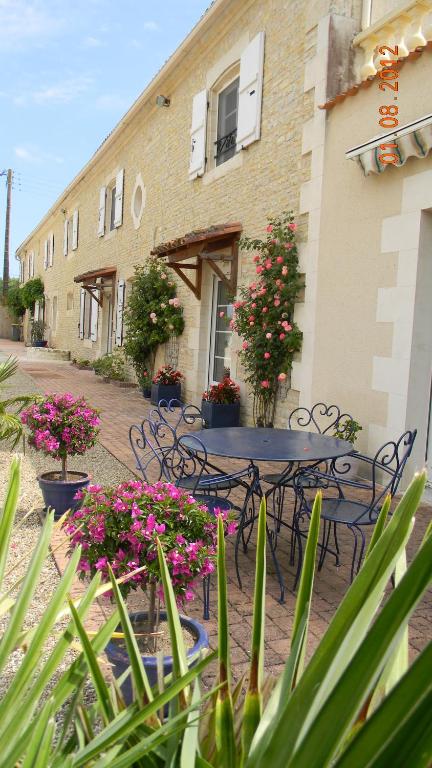 a table and chairs in front of a building with flowers at Le Logis d&#39;ANTIGNY in Val-du-Mignon