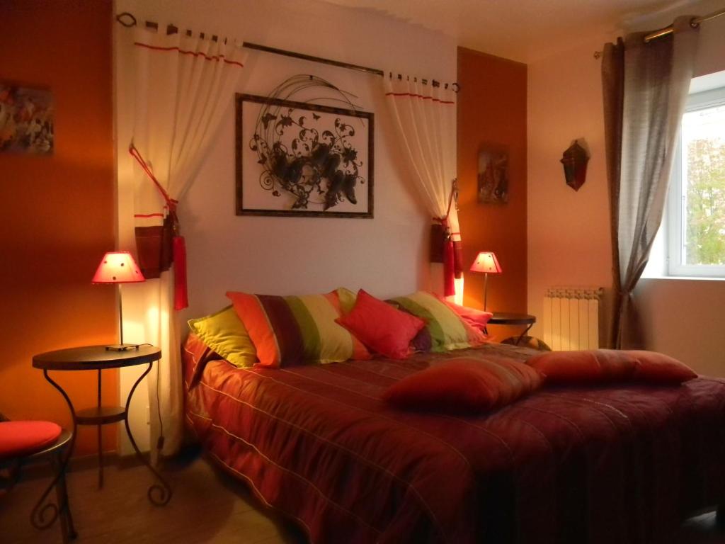 a bedroom with a bed with colorful pillows and a window at Le Logis d&#39;ANTIGNY in Val-du-Mignon