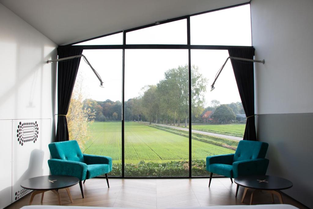 a waiting room with green chairs and a large window at De 6 Linden Gastronomisch Boutique Hotel in Sluis