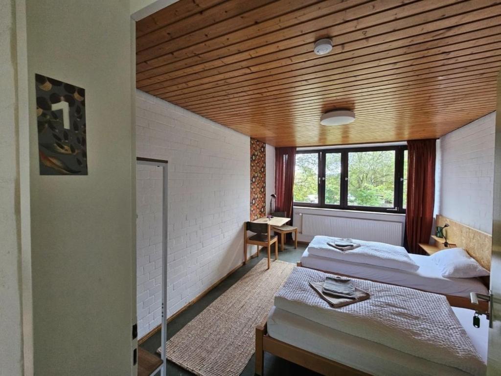 a bedroom with two beds and a wooden ceiling at Gästehaus am Sternberg in Gomadingen