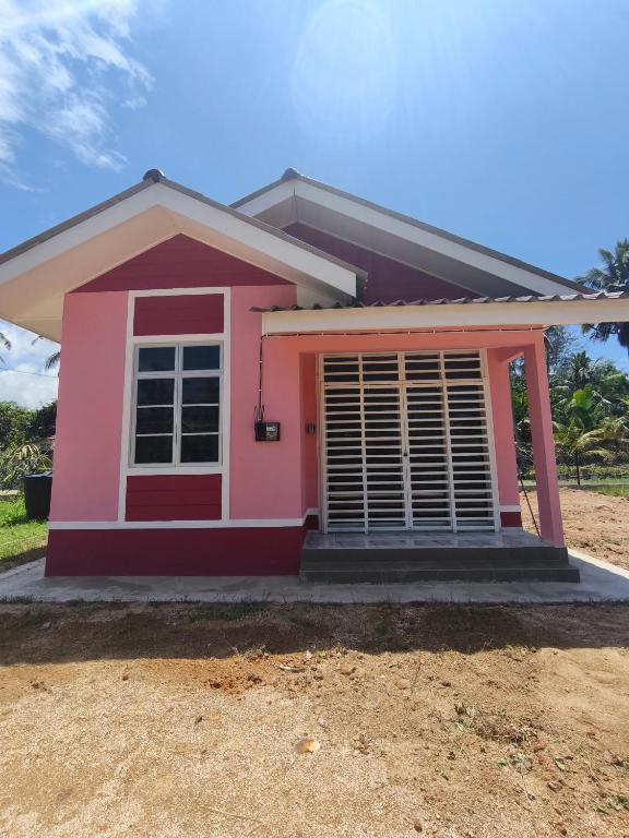 a pink house with the front door open at Asyhani Cottage in Bachok