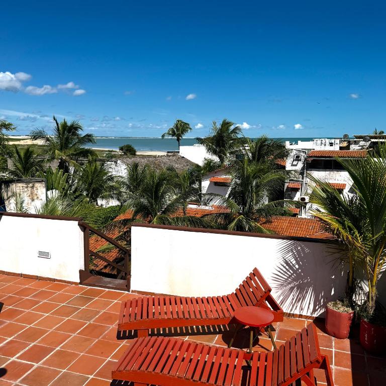 a patio with two chairs and the ocean in the background at Pousada Atlantis in Jericoacoara