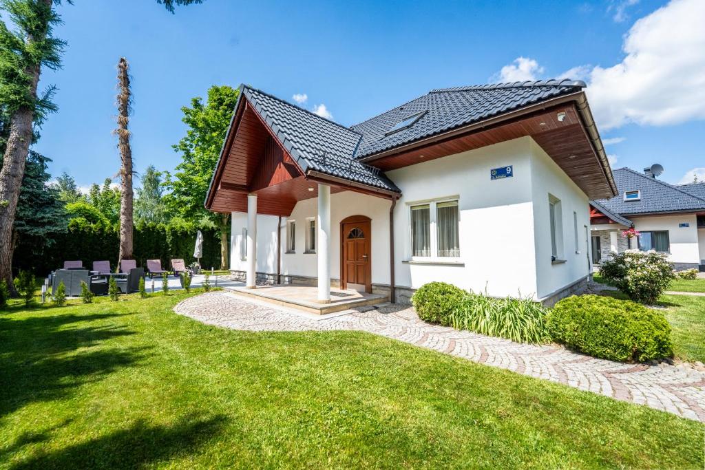 a house with a green yard and a house at Willa u Basi 2 in Miłków
