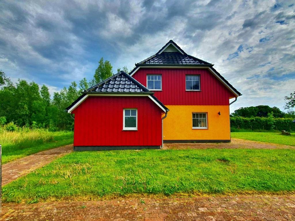 ein rot-gelbes Haus, das auf einem Feld steht in der Unterkunft Rood Huus in Dabitz