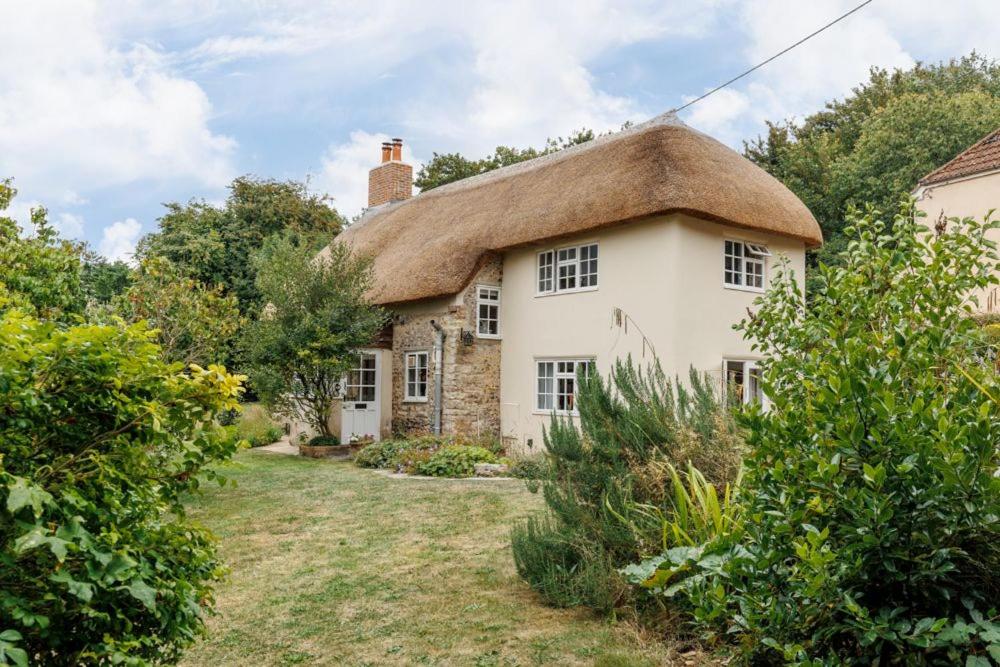 an old stone house with a thatched roof at Cheesemans Cottage in Grimstone