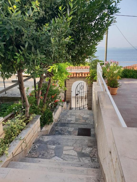 a stairway with a gate and trees and the ocean at Vicko villa in Seget Vranjica
