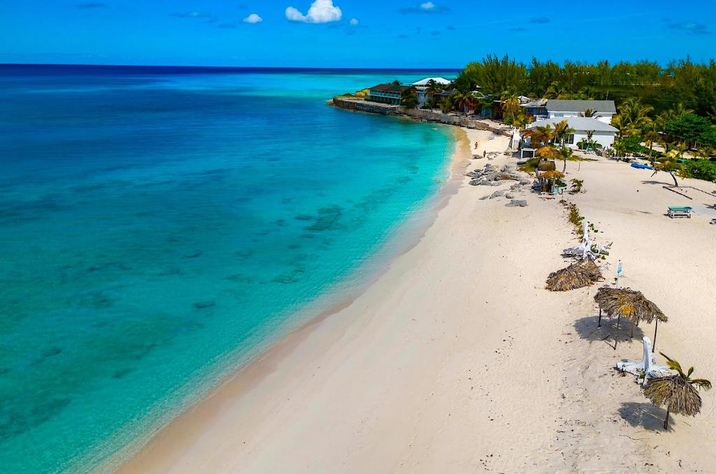 an aerial view of a beach with umbrellas and the ocean at The Sands Hotel in Cockburn Town
