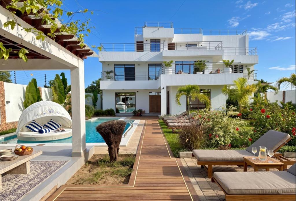a villa with a swimming pool and a house at Casa Samara in Diani Beach