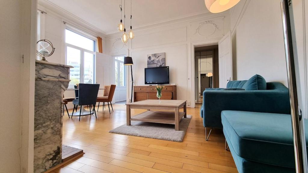 a living room with a blue couch and a table at AGENCE MOMENT'APART Legend in Mouvaux