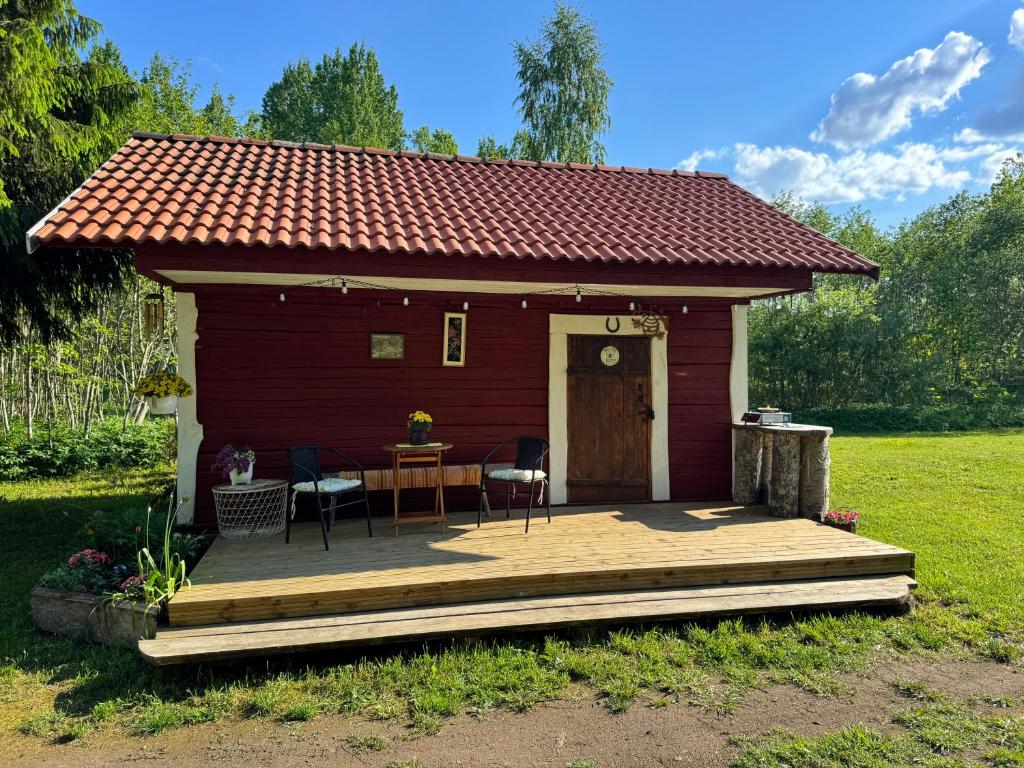 a red cabin with a table and chairs on a deck at Salatse metsa mesionn in Salatse