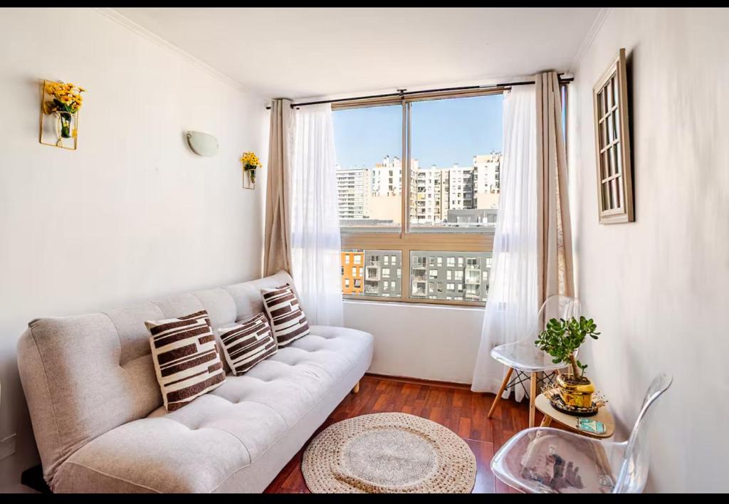 a living room with a couch and a large window at Lupe&Lulu aparments in Santiago
